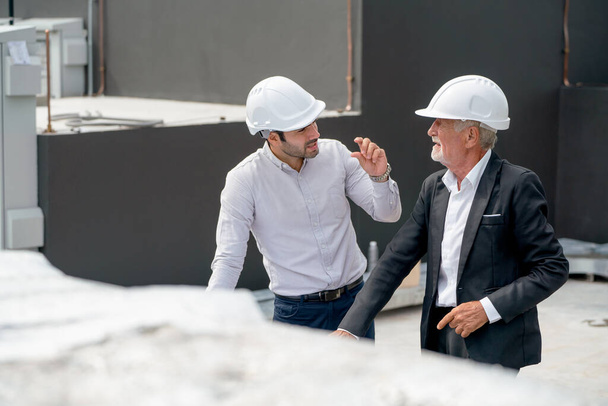 Высокий обзор двух инженеров или техников обсуждают вместе на крыше строения. - Фото, изображение