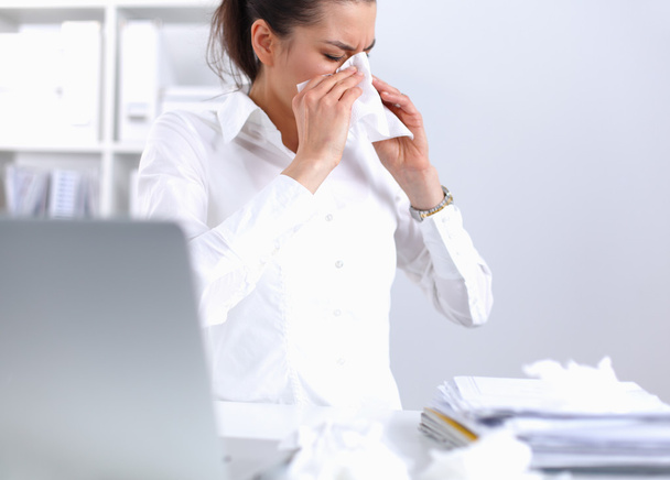 Young businesswoman blowing her nose, sits at the desk - Fotó, kép