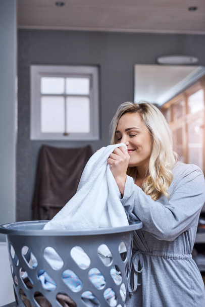 I just love the fresh smell of clean laundry. a young woman smelling fresh and clean laundry at home - Fotografie, Obrázek