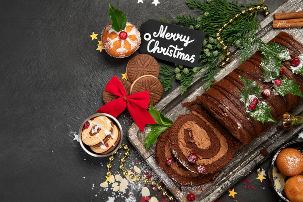 Chocolate yule log on dark background. Traditional dessert of Christmas time. Top view, copy space - Foto, Imagem