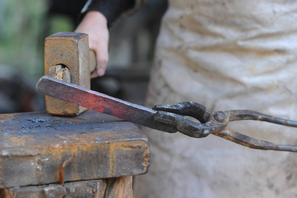 Almaty, Kazakhstan - 09.24.2015 : A blacksmith makes a metal holder for knives and tools in the workshop. - Foto, afbeelding