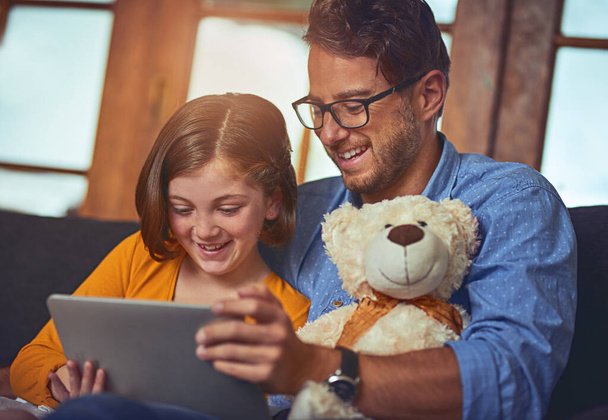 Виховання технічно дивовижної дочки. батько і дочка використовують цифровий планшет разом на дивані вдома
 - Фото, зображення