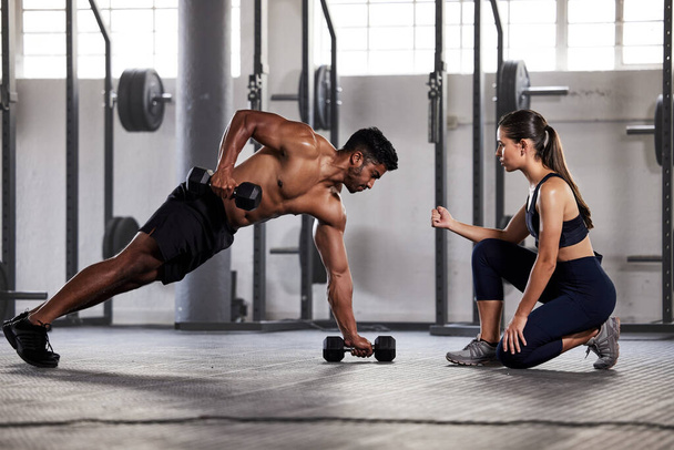 Muscular, sports man with female gym instructor or fitness coach doing body building workout, push up plank exercise. Active male athlete weightlifting in wellness center with trainer for motivation - Foto, imagen