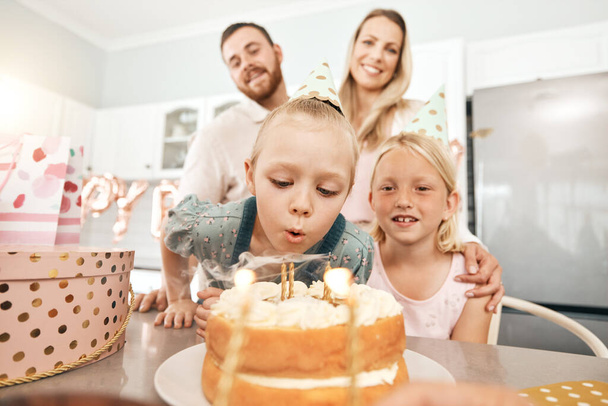 Children birthday party, cake and candles for blowing out with mother, father or sister in home kitchen. Fun, excited or happy kids celebrating, enjoying and having fun with parents on special event. - Photo, Image