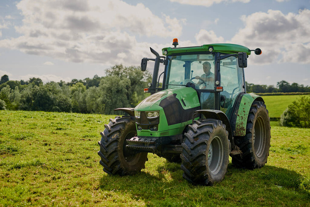 Каждой ферме нужен трактор. Полная длина снимка зеленого трактора на открытом участке фермы - Фото, изображение