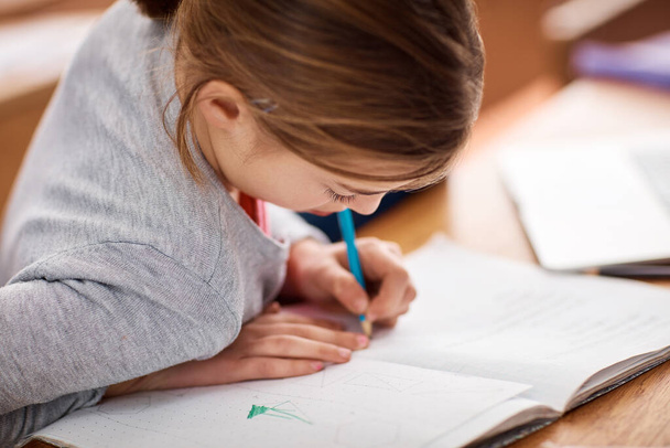 Наполняет свою рабочую тетрадь знаниями. школьница, пишущая в блокноте в классе - Фото, изображение