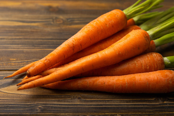 Frische Karotten auf braunem Hintergrund. Zutat für Salat.Vegetarisches Bio-Gemüse.Gesundes Lebensmittel.Kopierplatz.Platz für Text - Foto, Bild
