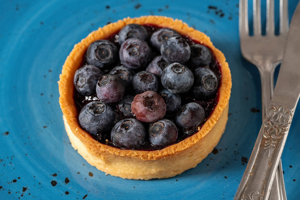 Freshly baked blueberry tart on a blue porcelain plate - Foto, imagen