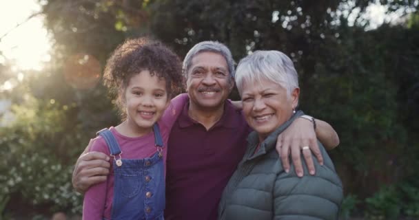 Smiling, happy and loving grandparents bonding with their cute granddaughter in a park, garden or yard on a sunny day outdoors. Portrait of a loving family relaxing, laughing and having fun together. - Séquence, vidéo