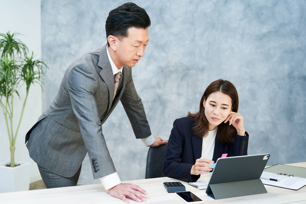 A woman communicating with a male employee with a complicated expression - 写真・画像