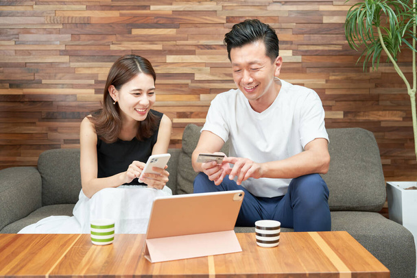 Мужчина и женщина делают покупки онлайн на диване - Фото, изображение