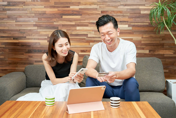 Man and woman shopping online on the sofa - Foto, afbeelding