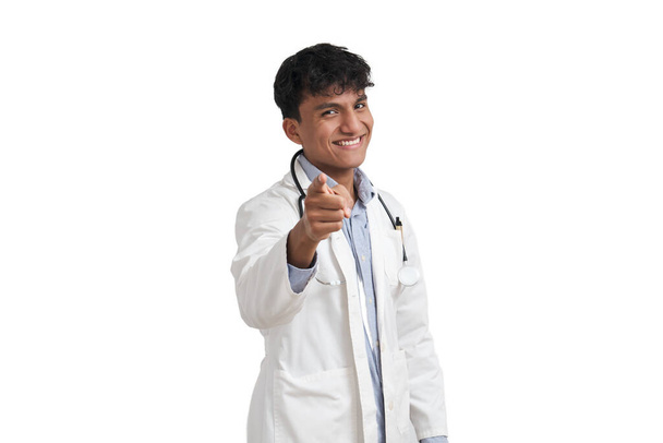 Portrait of a young peruvian male doctor smiling and pointing at camera. Isolated over white background. - Foto, Imagem