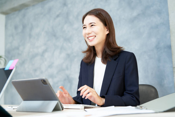 Ділова жінка працює на столі з посмішкою в офісі
 - Фото, зображення