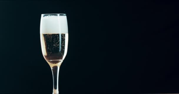 Sparkling alcohol, champagne and drink in a clear glass against black background with copy space. Bubbly, foamy and fizzy beverage for celebration, holiday or party. Sharing a toast for event. - Video