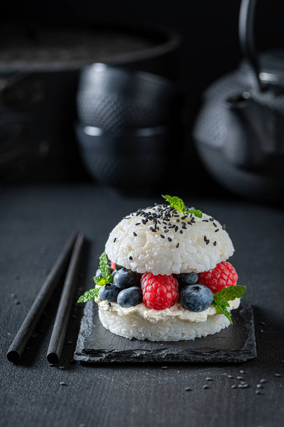 Unique and tasty sushi burger with berries and mascarpone as Japanese cuisine. Japanese dessert made of fruits and rice. - Fotó, kép