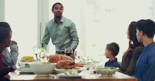 Interracial family celebrating during lunch party, making a toast and enjoying Christmas holiday together at home. Father giving cheers and eating dinner during Thanksgiving with children and wife. - Filmagem, Vídeo
