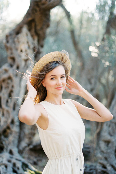 Young woman holding a straw hat on her head against the wind. High quality photo - Photo, Image
