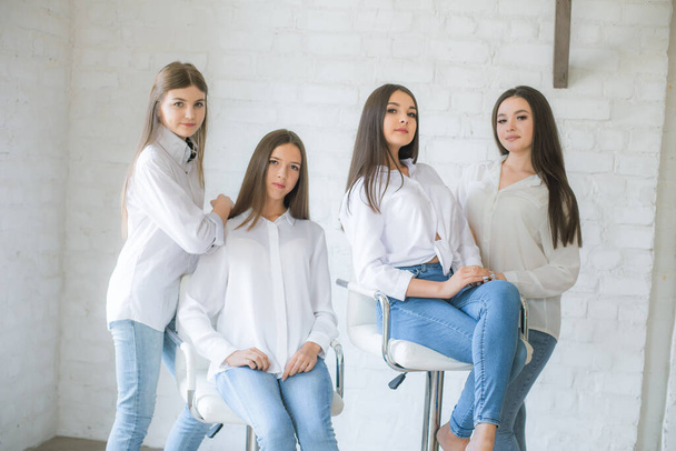 Pretty teenage girls models in trendy jeans and white shirts in the studio against the background of a white brick wall. Teenage fashion. beauty and fashion - 写真・画像