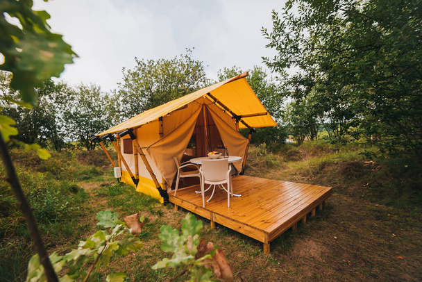 Gün batımında içinde ışık olan rahat, göz alıcı bir çadır. Yaz tatili ve tatil için lüks kamp çadırı. Yaşam tarzı kavramı - Fotoğraf, Görsel