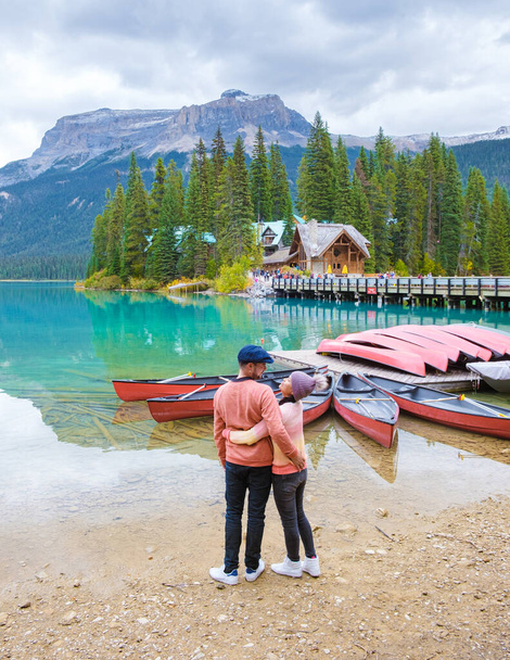 Emerald λίμνη Yoho εθνικό πάρκο Καναδάς Βρετανική Κολομβία. όμορφη λίμνη στα καναδικά Βραχώδη Όρη κατά την φθινοπωρινή περίοδο. Δύο άντρες και γυναίκες στέκονται δίπλα στη λίμνη. - Φωτογραφία, εικόνα