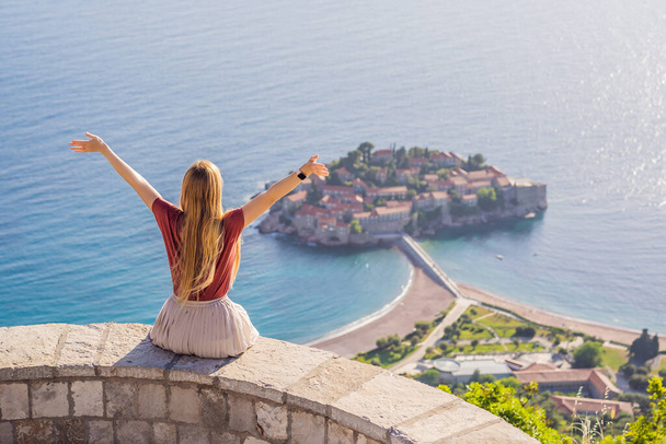 Woman tourist on background of beautiful view of the island of St. Stephen, Sveti Stefan on the Budva Riviera, Budva, Montenegro. Travel to Montenegro concept. - Foto, afbeelding