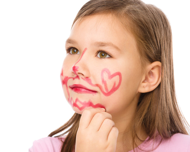 Little girl is applying lipstick on her cheek - Zdjęcie, obraz