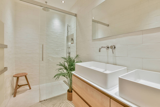 Fragment of interior of modern white bathroom with wooden cabinet under sink and with mirror and towel - Foto, Imagem