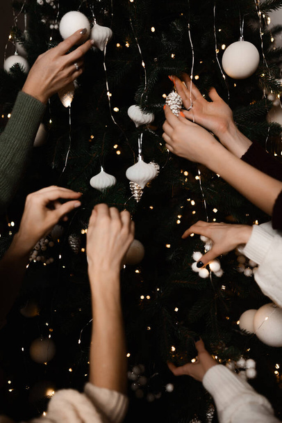 close-up of the hands of the girls decorate the Christmas tree with white balls - Foto, imagen