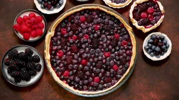 Homemade fresh round cake tart with berries, raspberries, blackberries, red and black currant jelly. Top view, flat lay on dark rustit table - Video, Çekim
