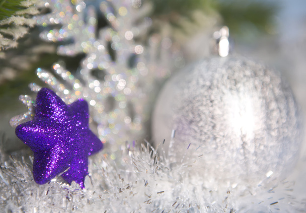Dekoratives violettes Spielzeug, eine Schneeflocke und ein silberfarbener Neujahrsball aus dem Fokus - Foto, Bild
