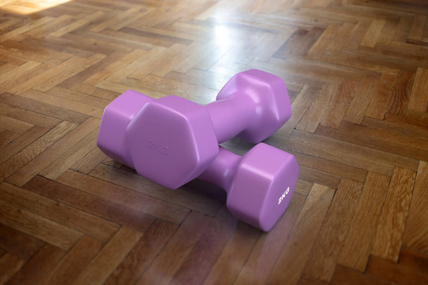 Понятие здорового образа жизни. Фиолетовая гантель весом 2 кг на деревянном полу. Тренировки мышц, упражнения для тела, спорт, фитнес. Вид сверху. 3D рендеринг - Фото, изображение
