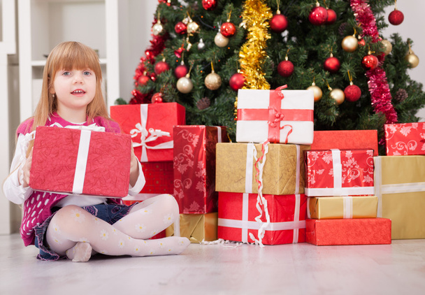 Pretty little girl smiling with present near the Christmas tree  - Foto, Bild