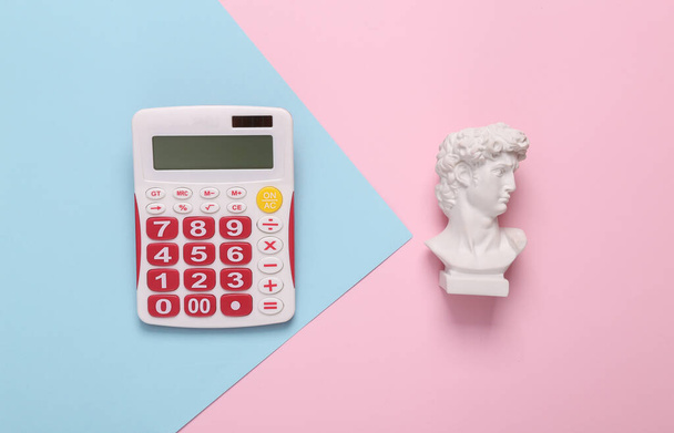 Bodegón minimalista. Concepto pop. Busto David con calculadora sobre fondo azul rosado. Vista superior - Foto, imagen
