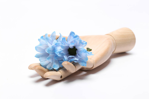 Wooden hand holding blue flowers isolated on white background - 写真・画像