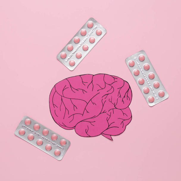 Χαρτοκομμένο μυαλό με χάπια σε ροζ φόντο. Θεραπεία κεφαλαλγίας - Φωτογραφία, εικόνα