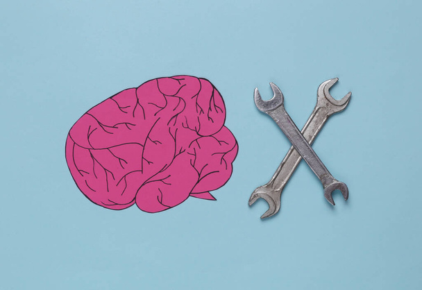 Paper-cut brain and wrenches on a blue background. Mental health, treatment - Fotó, kép