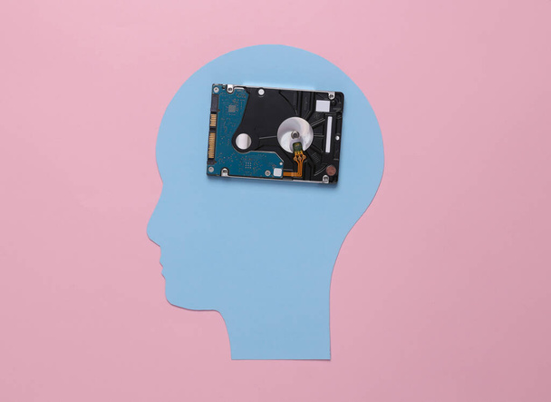 The concept of saving memories. Paper cut head with hard drive on pink background - Foto, Imagen