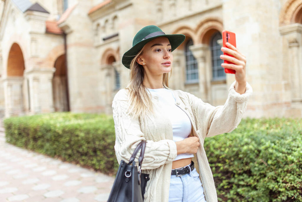 Cute fashion woman in felt hat using smartphone in the city - Fotoğraf, Görsel