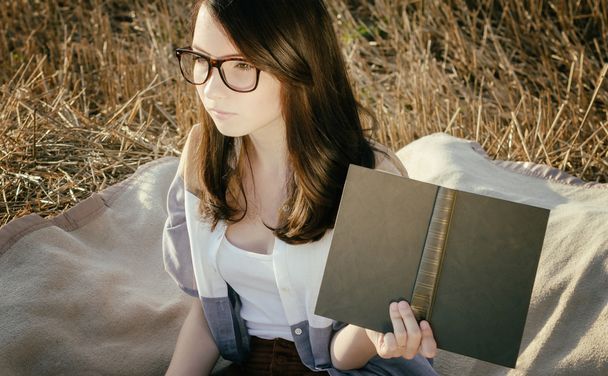 young unusual girl illustrates conceptual idea with book - Photo, Image