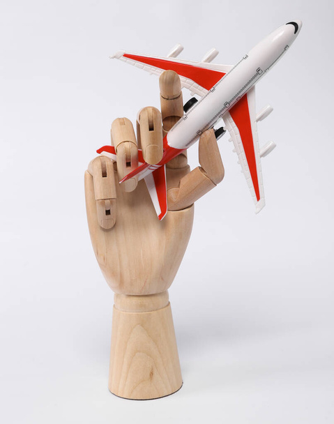 Wooden hand holding airplane model isolated on white background - Foto, Bild