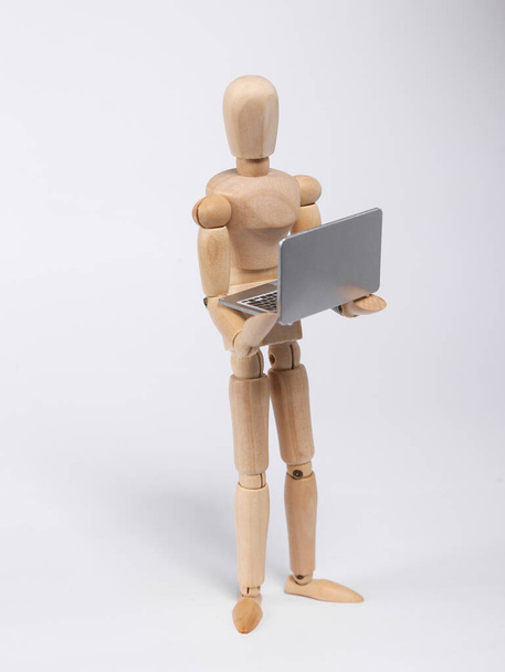 Wooden puppet uses laptop isolated on white background - Foto, Imagem