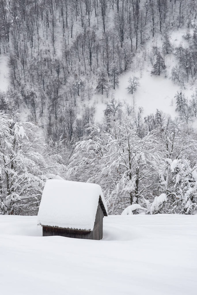 Χειμερινή θέα με ξύλινη καλύβα στο χιόνι μετά από χιονόπτωση σε ορεινό χωριό - Φωτογραφία, εικόνα