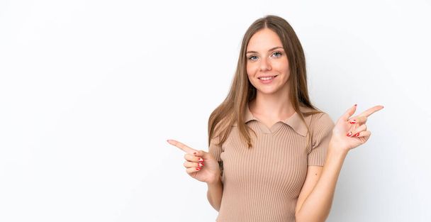 Giovane donna lituana isolata su sfondo bianco che punta il dito verso i laterali e felice - Foto, immagini