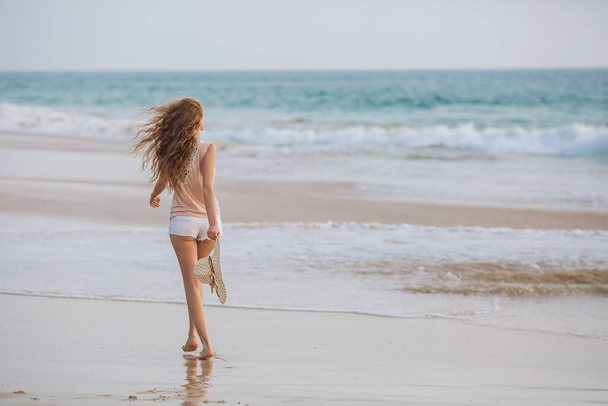 Retrato de mujer joven en bikini blanco en la playa tropical mirando a la cámara. Hermosa chica latina en traje de baño con espacio para copiar. Vacaciones de verano y concepto de bronceado
. - Foto, Imagen