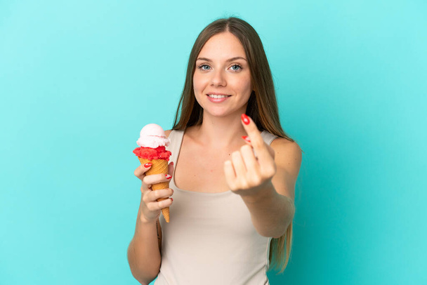 Young Lithuanian woman with cornet ice cream isolated on blue background doing coming gesture - Фото, зображення