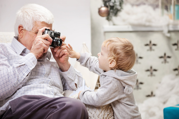 Hombre mayor tomando fotos de su nieto en Navidad
 - Foto, Imagen