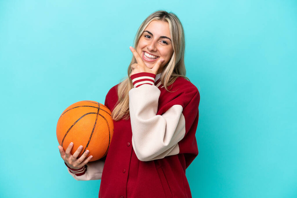 Young caucasian basketball player woman isolated on blue background happy and smiling - Fotoğraf, Görsel