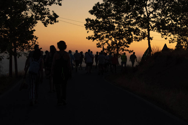 Group of silhouettes at sunset of people walking along the road from Viznar to Alfacar on the occasion of the popular march in tribute to Federico Garcia Lorca and victims of Francoism - Foto, Imagen
