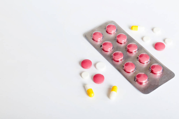 Blister package with Vitamin on color background. Medicine pills on a light background. Medicines and prescription pills flat lay background. pink medical tablets in blister. - 写真・画像